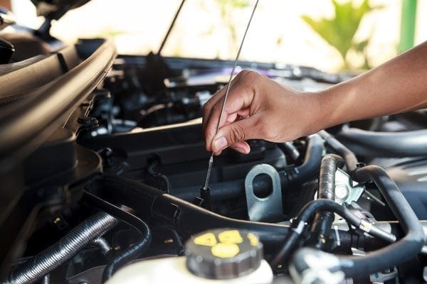 Mechanic checking oil dip-stick under car hood