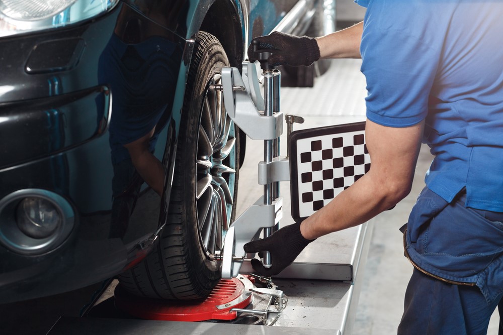 An image of a mechanic performing a wheel alignment service.